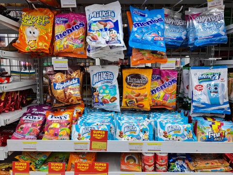 various brands and types Candy and confectioneries, including Mentos and Milkita, displayed on shelves in a grocery store or convenience store. Snack food, retail, and consumer goods.