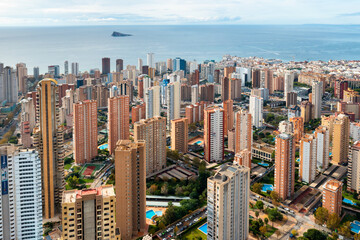 Naklejka premium Panoramic city view of Benidorm modern skyline with high-rise hotels, beachside resorts, and the sparkling Mediterranean Sea. Popular tourist destination in the Alicante region of Spain.