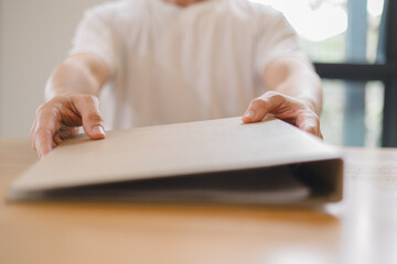 handing over a brown folder across the desk, concept for document delivery, business agreement, contract signing professional office communication.