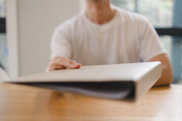 handing over a brown folder across the desk, concept for document delivery, business agreement, contract signing professional office communication.