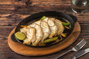 Grilled sea bass fillet served on skillet with vegetables