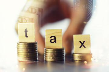 Tax wooden letter on wooden block.Pay tax .Income tax return. Double exposure city, dollar.