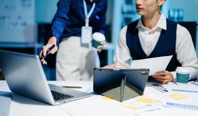 Businessman hand using laptop and tablet with social network diagram and two colleagues discussing data on desk as concept