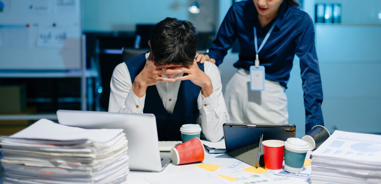 Asian businesswoman comforting stressed coworker in modern office, showing empathy, teamwork, and emotional support at workplace.