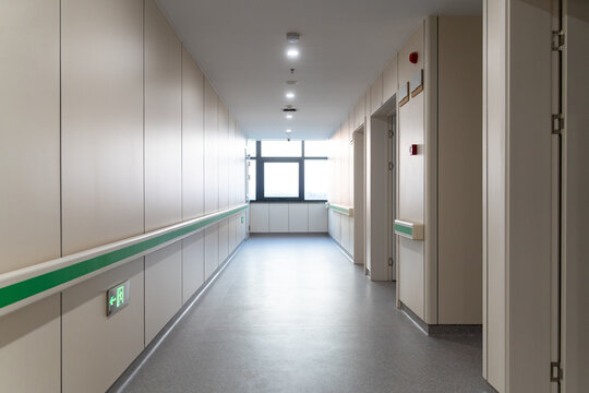  clean hospital corridor with green handrails, doors, and bright lights