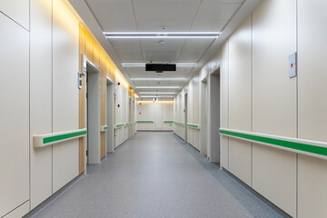  clean hospital corridor with green handrails, doors, and bright lights