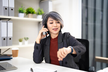 Businesswoman talk on mobile phone and check time on her wrist watch.
