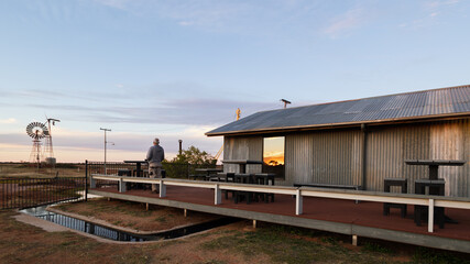 A man standing at a corrugated iron shed containing an historic hydro electricity system that uses...