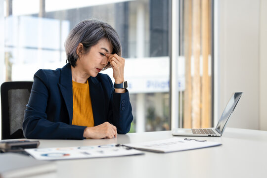 Asian businesswoman are serious at work causing headache stressed out with documents and laptop at the office.