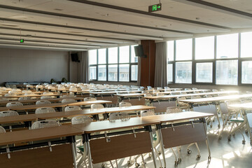 spacious conference room with rows of tables white chairs