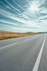 Open road under a vast sky with wispy clouds