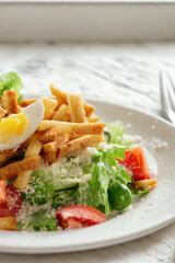 Fresh caesar salad with strawberries and egg on a white plate