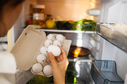 Female hand taking egg from a fridge