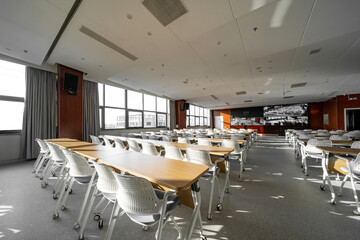 spacious conference room with rows of tables white chairs