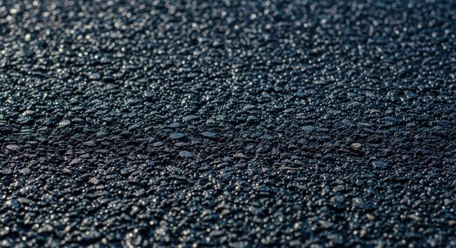 Close up of dark asphalt road surface showing the rough texture and aggregate, ideal for backgrounds and textures