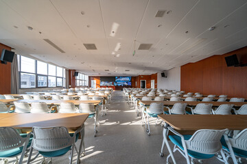 spacious conference room with rows of tables white chairs