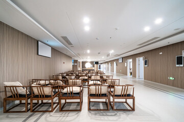 room with traditional wooden chairs, cushions, a wall-mounted screen, and bright lighting, blending modern and classic styles