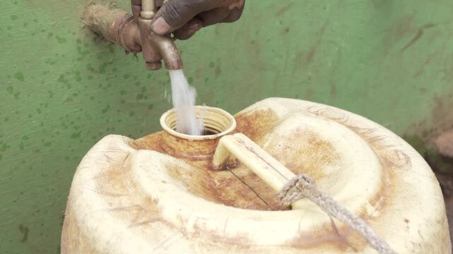 Jerry cans are filled with water at village well, water shortage Africa.