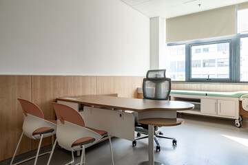 hospital examination room with a bed, desks, and large windows
