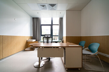 hospital examination room with a bed, desks, and large windows