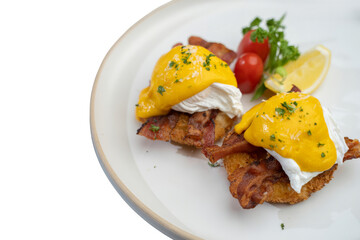 Delicious eggs benedict dish, showcasing poached eggs with creamy hollandaise sauce, bacon, served on a white plate