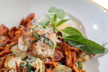 A close-up shot of a gourmet seafood pasta dish in a white bowl, showcasing the culinary artistry. The dish is garnished with fresh basil leaves.