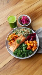 Healthy salmon salad with quinoa, kale, roasted veggies, and green juice on wooden table