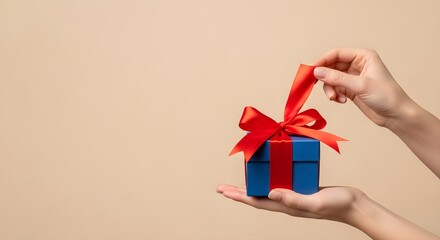 Excited Hands Opening Blue Gift Box with Red Ribbon on Beige Background, Celebrating Surprise, Christmas, Birthday, or Special Occasion