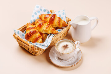 Aromatic croissants in wicker basket with cup of coffee