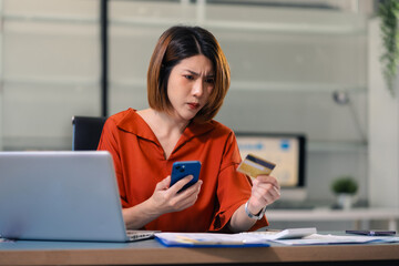 Serious woman cover her face after stressed with credit card debt sit at workplace desk in office use calculator calculates monthly expenses.