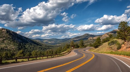 Naklejka premium Scenic winding road through mountainous landscape under a dramatic sky with fluffy clouds and lush greenery enhancing the serene beauty of nature