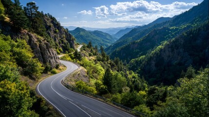Fototapeta premium Scenic Mountain Road Winding Through Lush Green Hills Under Blue Sky with Fluffy White Clouds and Majestic Mountain Range in the Background