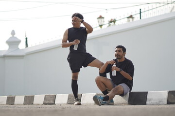 Asian Indonesian Men Resting and Drinking Water After Running