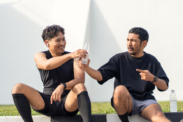 Asian Indonesian Men Resting and Drinking Water After Running