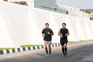 Asian Indonesian Men Running Outdoors with Water Bottles