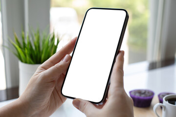 Female hand holding phone with isolated screen over table cafe