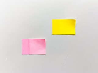 Two square sticky notes, one pink and one yellow, placed neatly on a clean white desk background. Minimalist composition suitable for office, planning, and creative workspace concepts.