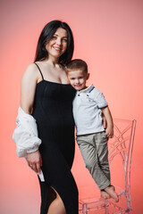 Joyful moment shared between a mother and her son against a vibrant pink backdrop showcasing love and connection before new beginnings