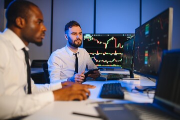 Team of traders working at monitor computer and browsing online in trading office