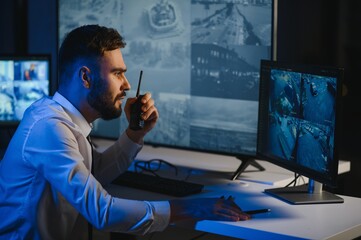 Security System CCTV Monitor Room. Man Using Walkie Talkie
