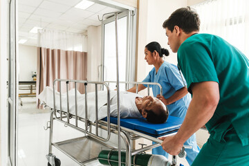 Medical staff work in collaboration as they transport a patient on a stretcher through a hospital...
