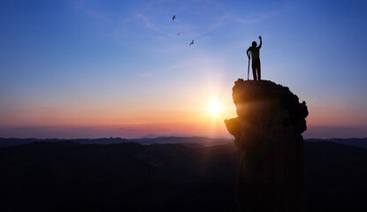 Silhouette a disabled man standing up and raising his hand at  sunrise background