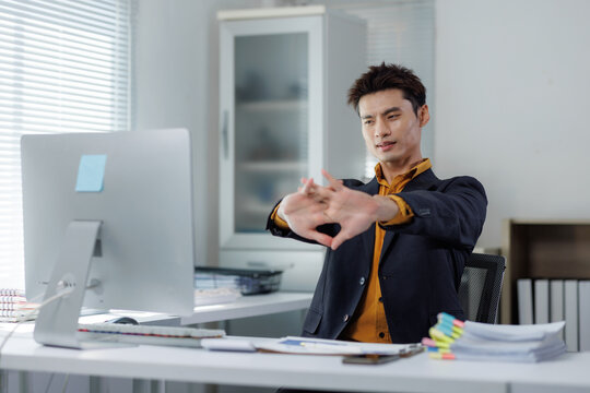 Young businessman stretching hands taking office break - Powered by Adobe