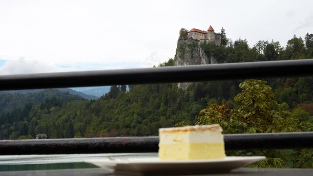 Traditional Bled cream cake Kremsnita dessert with whipped layers served at outdoor cafe with castle in backdrop