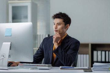 Naklejka premium Young asian businessman working on computer researching solutions