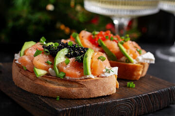 Avocado and salmon appetizer on the Christmas table. Canapes with fish and caviar.