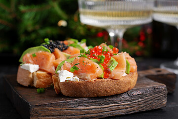 Avocado and salmon appetizer on the Christmas table. Canapes with fish and caviar.