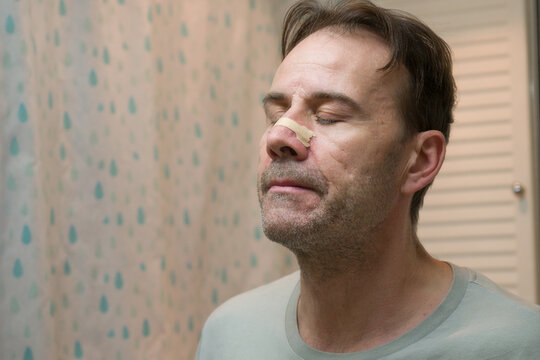 Man in the bathroom wearing anti snoring nasal strip breathing aid for better sleep quality.