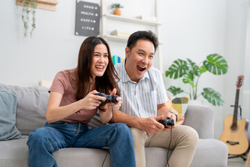 Asian loving couple enjoying games during holidays at cozy home. 