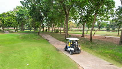 Drone view of group of golfers riding together in golf cart on course. 